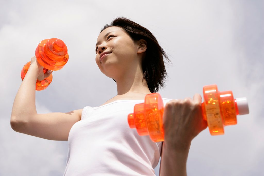 A woman exercising as she lifts up the dumbbells --- Image by © Image Werks/Corbis