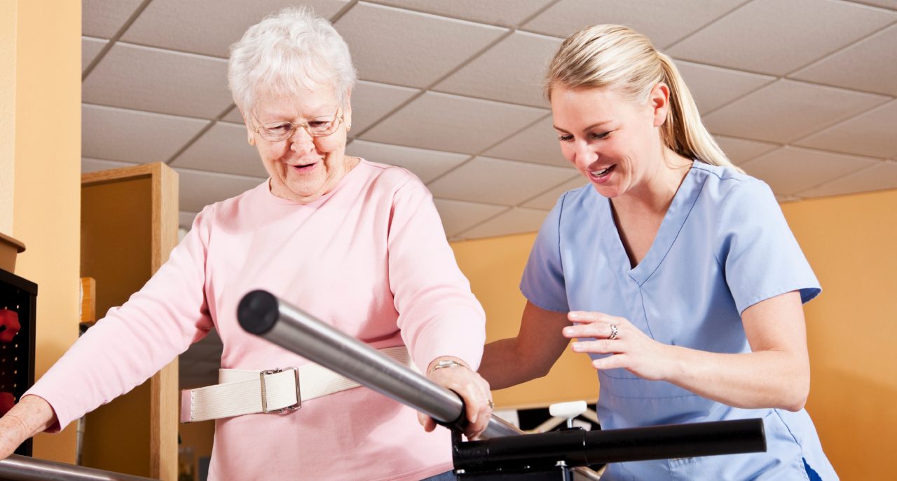 Physical therapist with senior woman, gait training Senior woman (80s) on parallel bars doing gait training with physical therapist (30s).