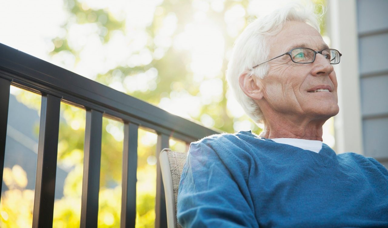 Senior man wearing eyeglasses relaxing on porch --- Image by © Hero Images/Corbis