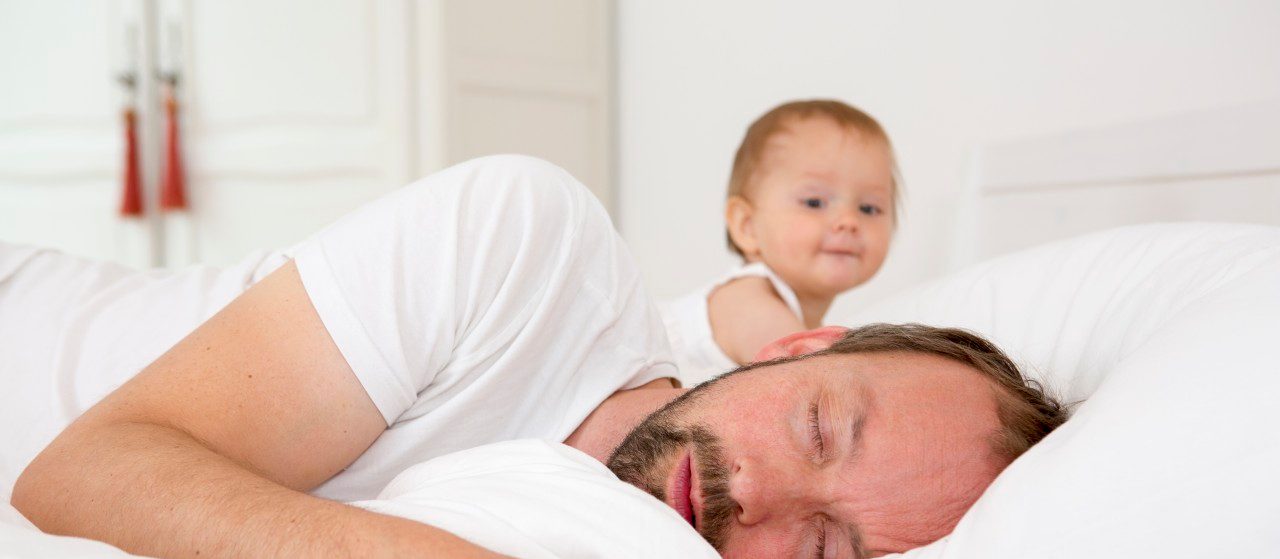 13 Jul 2014 --- Father asleep in bed, baby daughter watching --- Image by © Judith Haeusler/Corbis