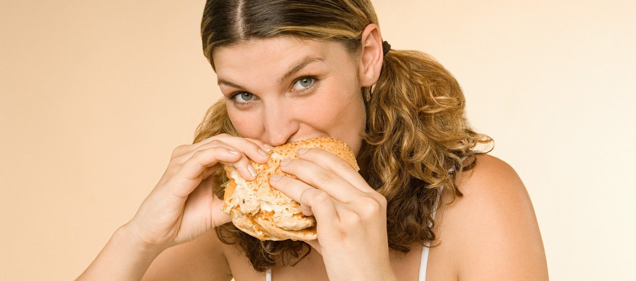 Woman eating a burger --- Image by © Image Source/Corbis