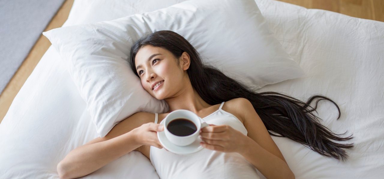 17 Oct 2014 --- Young woman lying on bed with a cup of coffee --- Image by © Lane Oatey/Blue Jean Images/Corbis