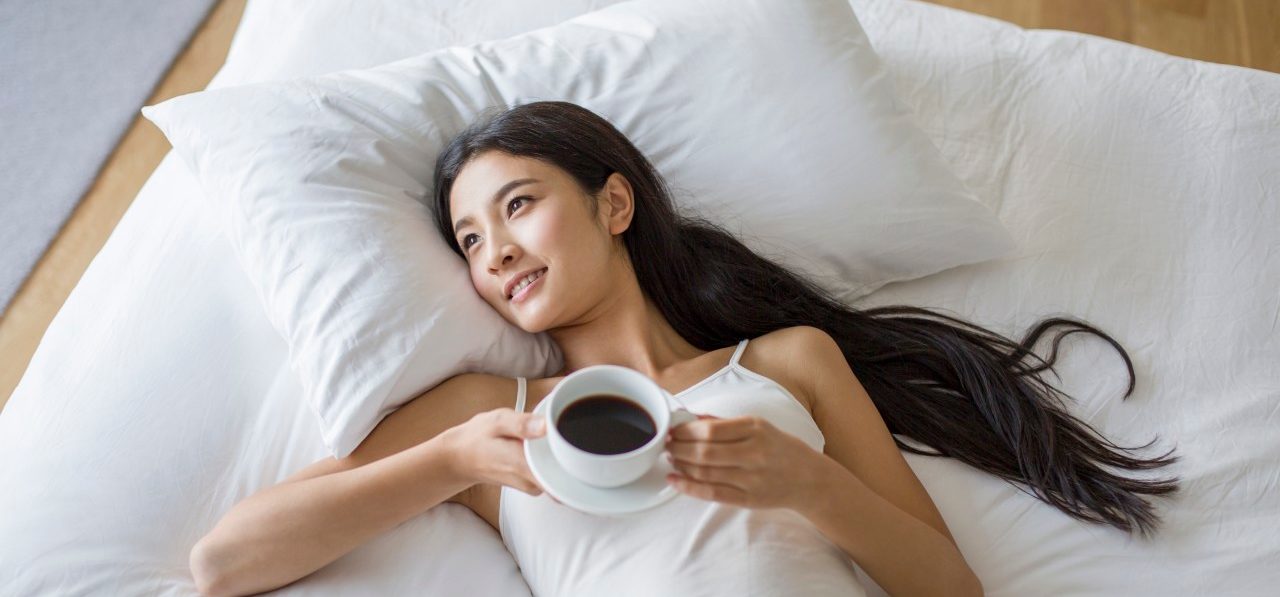 0042-11-30T00:00:00.000Z 17 Oct 2014 --- Young woman lying on bed with a cup of coffee --- Image by © Lane Oatey/Blue Jean Images/Corbis