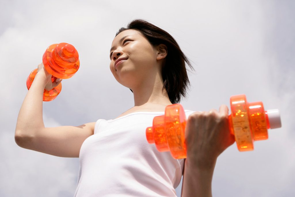 A woman exercising as she lifts up the dumbbells --- Image by © Image Werks/Corbis