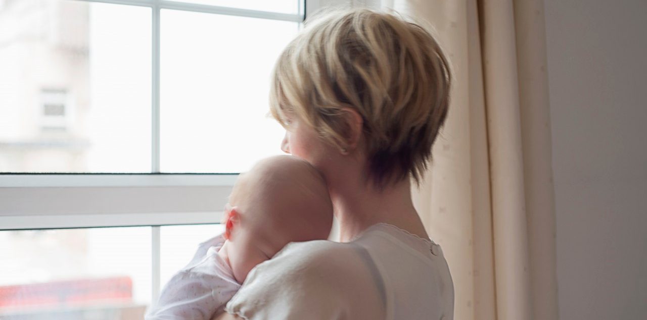 25 Nov 2014 --- Mother carrying sleeping baby girl, looking out window --- Image by © Cecilia Cartner/Corbis
