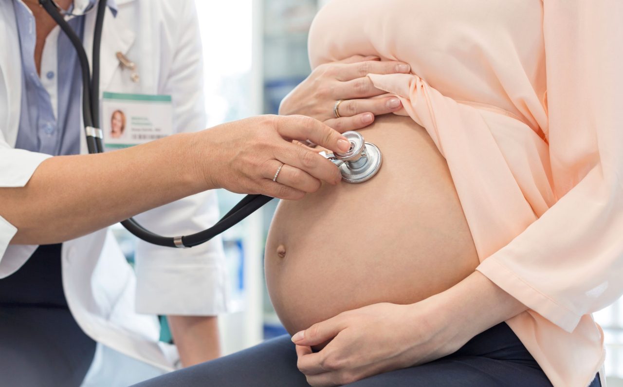 A doctor listens to a baby's heartbeat in a woman's womb A doctor listens to a baby's heartbeat in a woman's womb