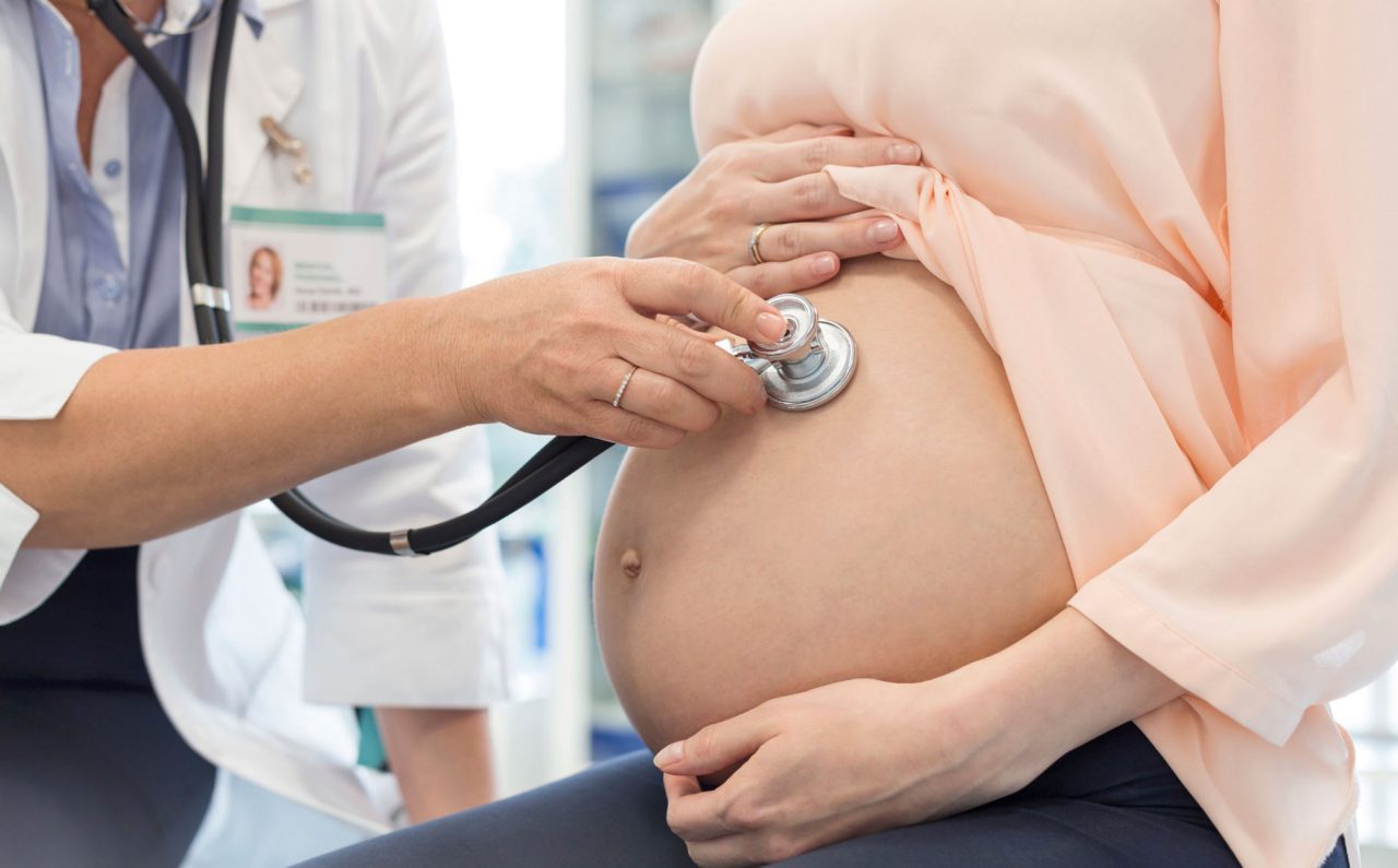 A doctor listens to a baby's heartbeat in a woman's womb