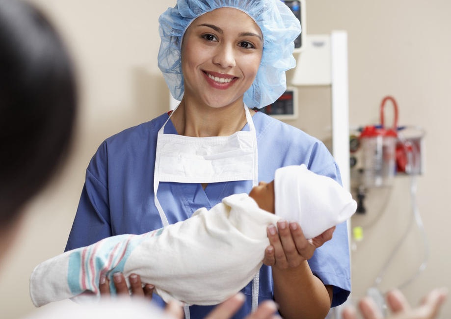 Physician Handing Newborn to Mother --- Image by © Jack Hollingsworth/Corbis