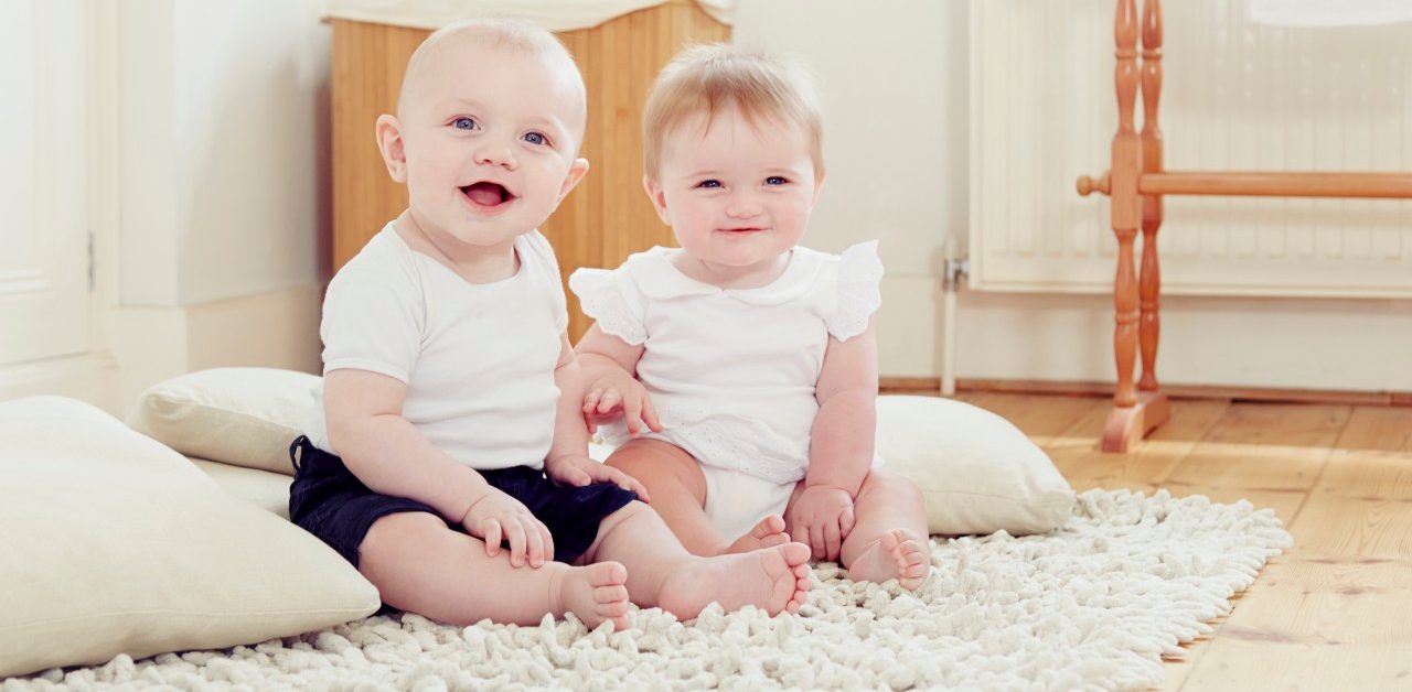 18 Jun 2014 --- Portrait of smiling baby girl and baby boy sitting on rug --- Image by © Emma Kim/Cultura/Corbis