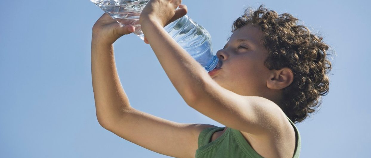 Low angle of young boy drinking water --- Image by © Steve Sparrow/cultura/Corbis