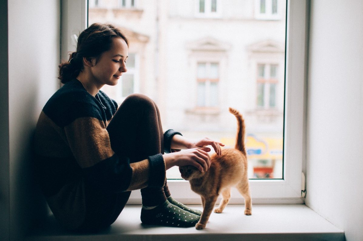 Girl sitting with cat on windowsill --- Image by © Oleh Slobodeniuk/Corbis