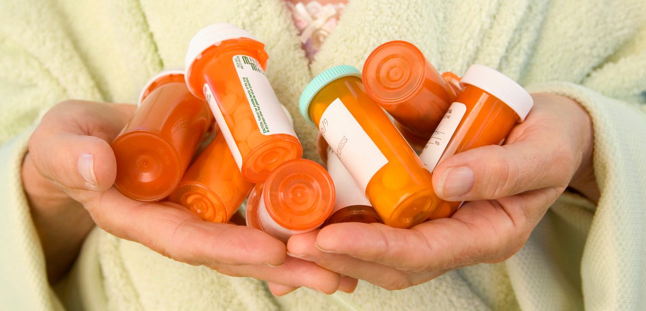 Senior Woman Holding Pill Bottles --- Image by © Paul Barton/Corbis