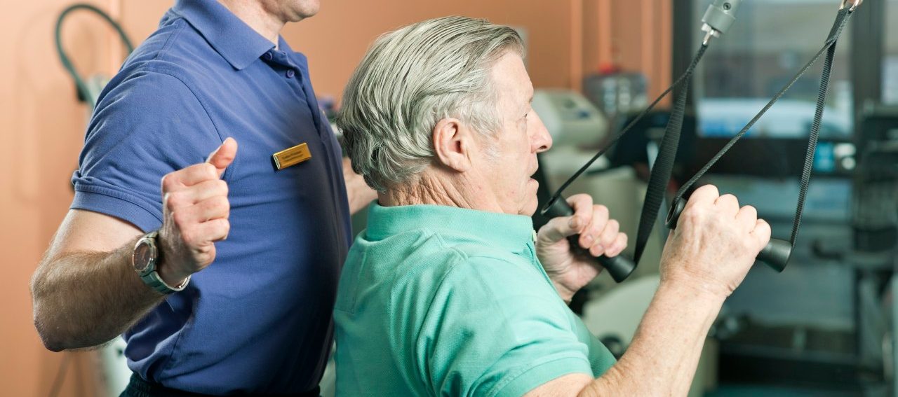 Trainer helping older man exercise --- Image by © Colin Hawkins/cultura/Corbis