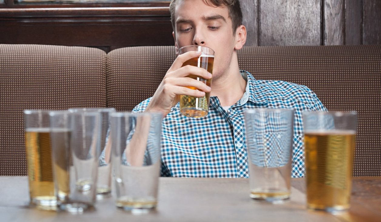 Young man drinking beer in bar --- Image by © Image Source/Corbis