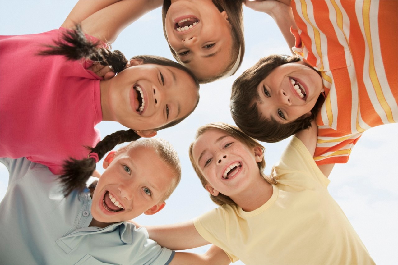 West New York, New Jersey, USA --- Smiling children huddling together --- Image by © KidStock/Blend Images/Corbis