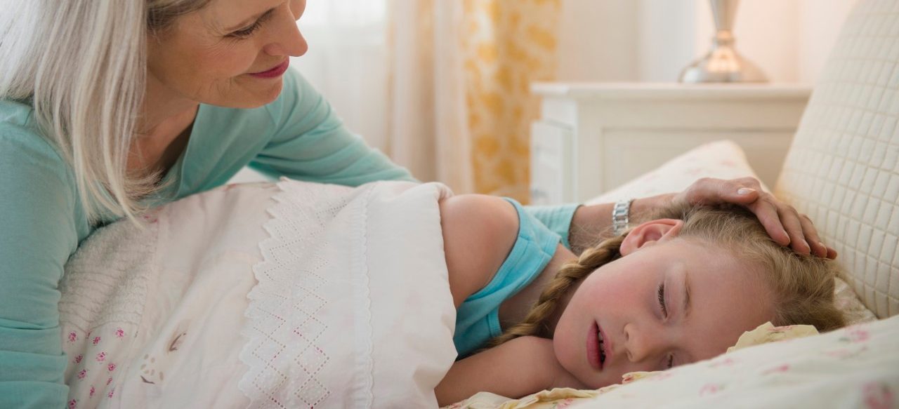 31 Jan 2014 --- Senior Caucasian woman putting granddaughter to bed --- Image by © JGI/Jamie Grill/Blend Images/Corbis