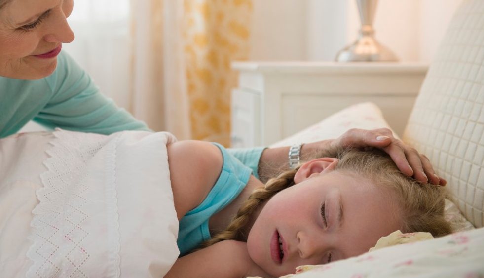 31 Jan 2014 --- Senior Caucasian woman putting granddaughter to bed --- Image by © JGI/Jamie Grill/Blend Images/Corbis