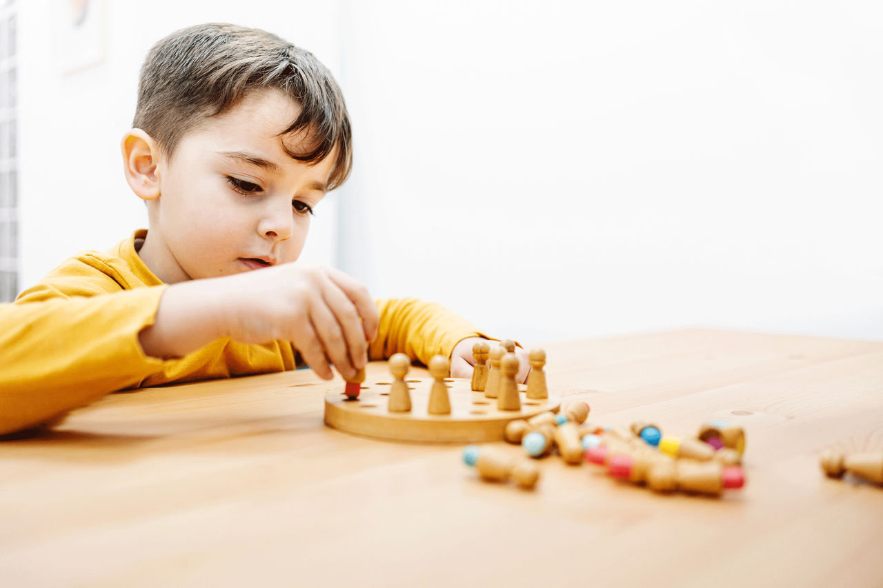 Autism therapy, Child placing colored squares in sequence on table.   Source: 85039_1_Thinkstock_105088879