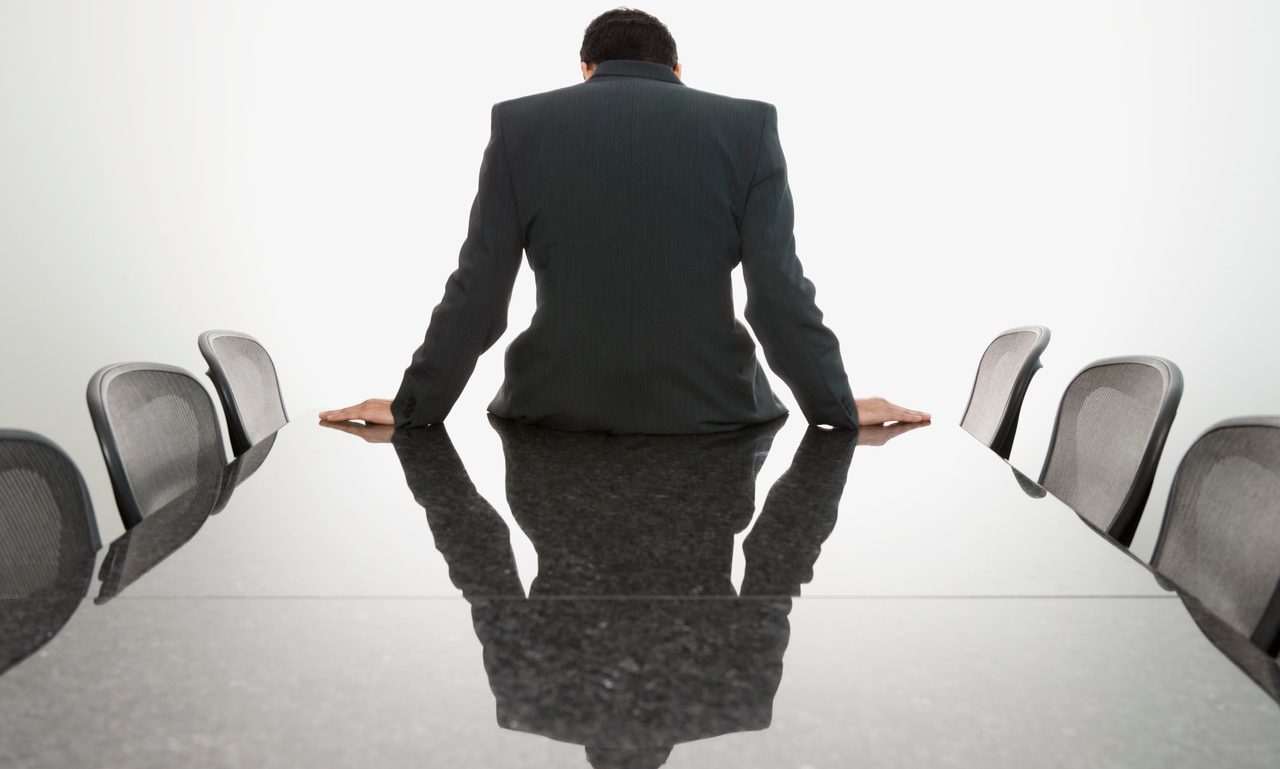 Businessman sitting slouched on edge of conference table --- Image by © Steve Hix/Somos Images/Corbis
