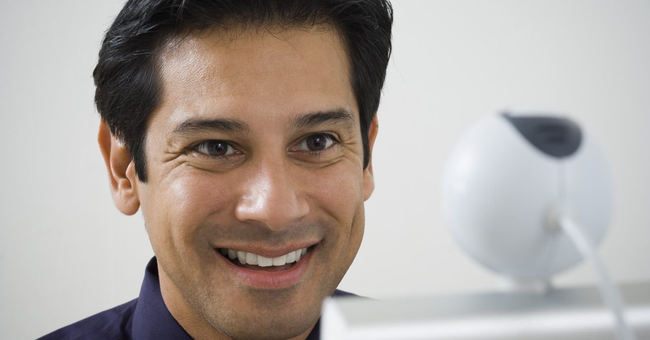 Close-up of a mature man smiling in front of a video conference camera --- Image by © Rubberball/Corbis
