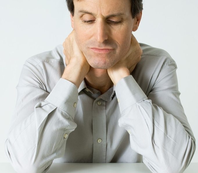 42-21582198 Man Sitting Next To Pills, Holding Neck, Looking Down --- Image by © Michele Constantini/PhotoAlto/Corbis