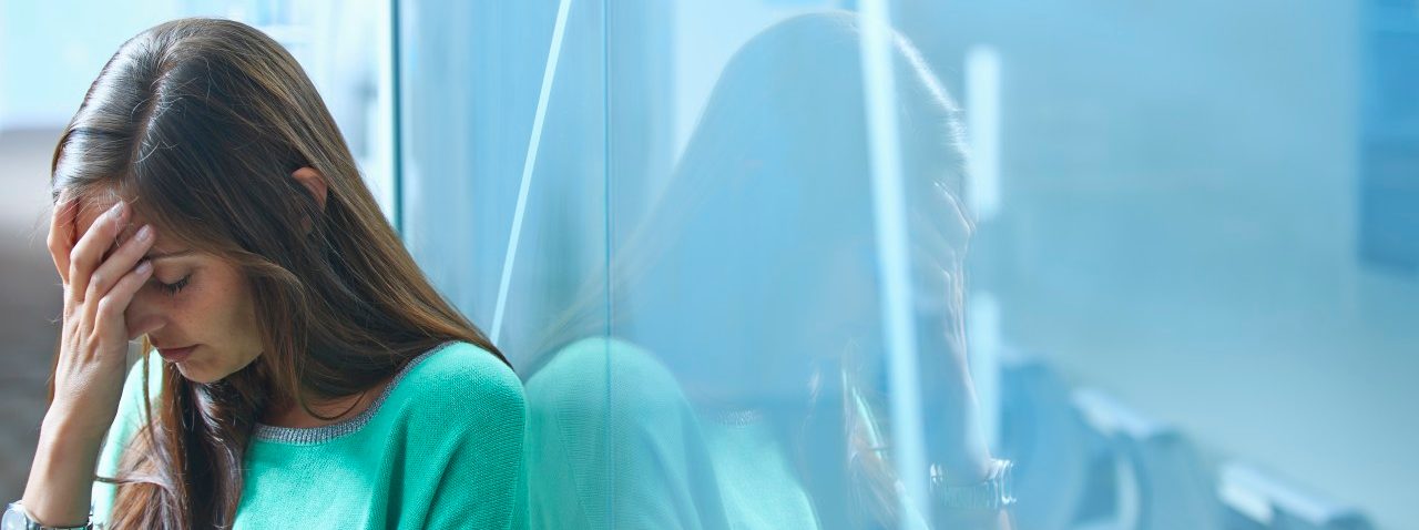 25 Apr 2014 --- Mid adult businesswoman leaning against glass wall in office with hand on face --- Image by © Ghislain & Marie David de Lossy/Corbis
