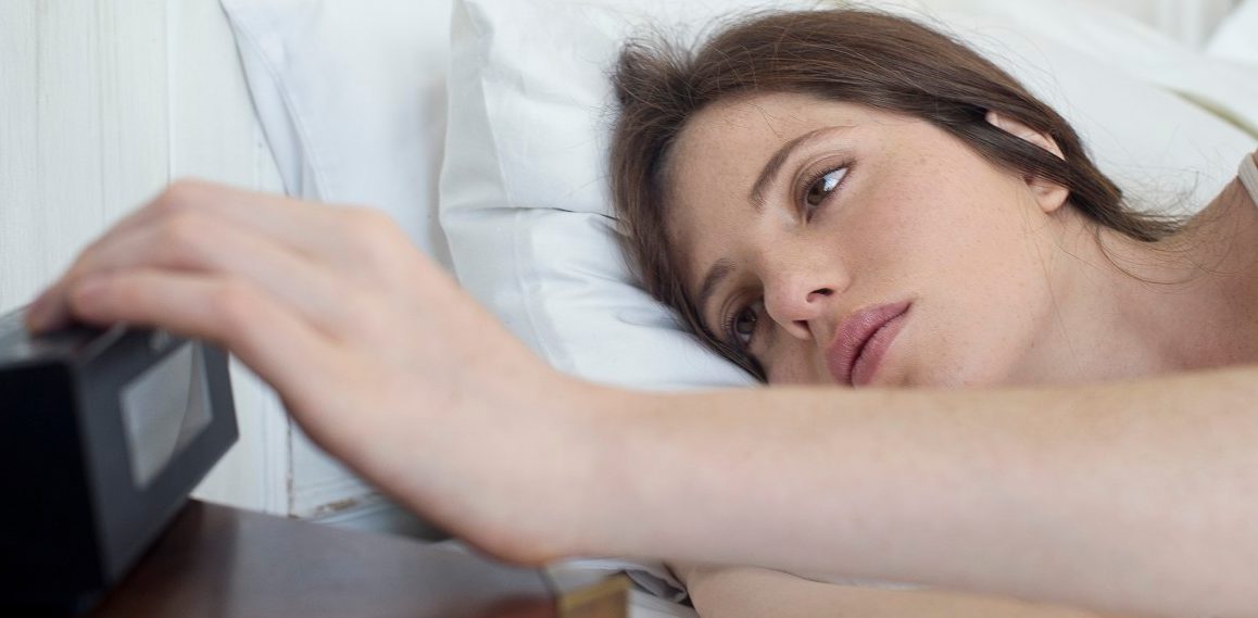 18 Feb 2014 --- Woman in bed pressing alarm clock snooze button --- Image by © Frederic Cirou/PhotoAlto/Corbis