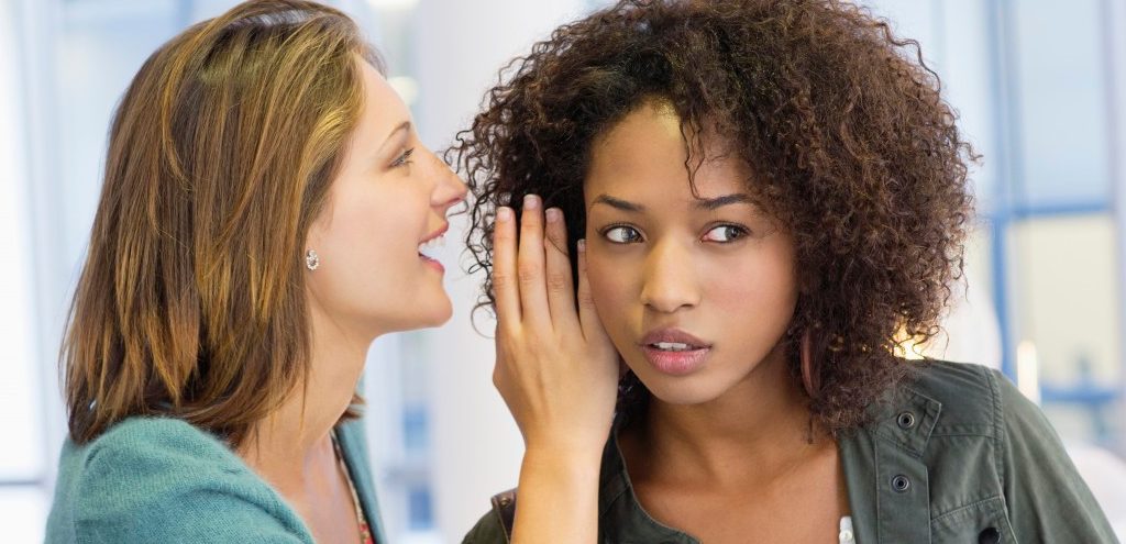 Side profile of a woman whispering in her friend's ear in university --- Image by © Eric Audras/Onoky/Corbis