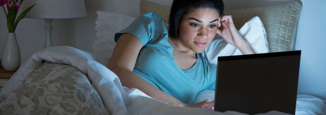 USA, New Jersey, Jersey City, Young woman using laptop in bed --- Image by © Tetra Images/Corbis