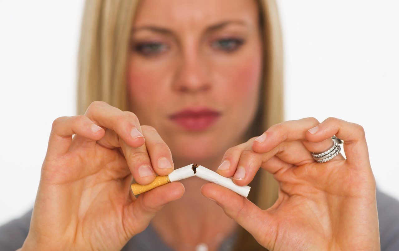 Young woman breaking cigarette --- Image by © Tetra Images/Corbis