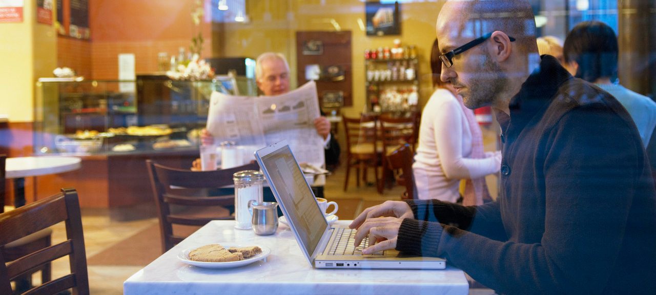 Man in coffee shop using laptop computer --- Image by © Beau Lark/Corbis