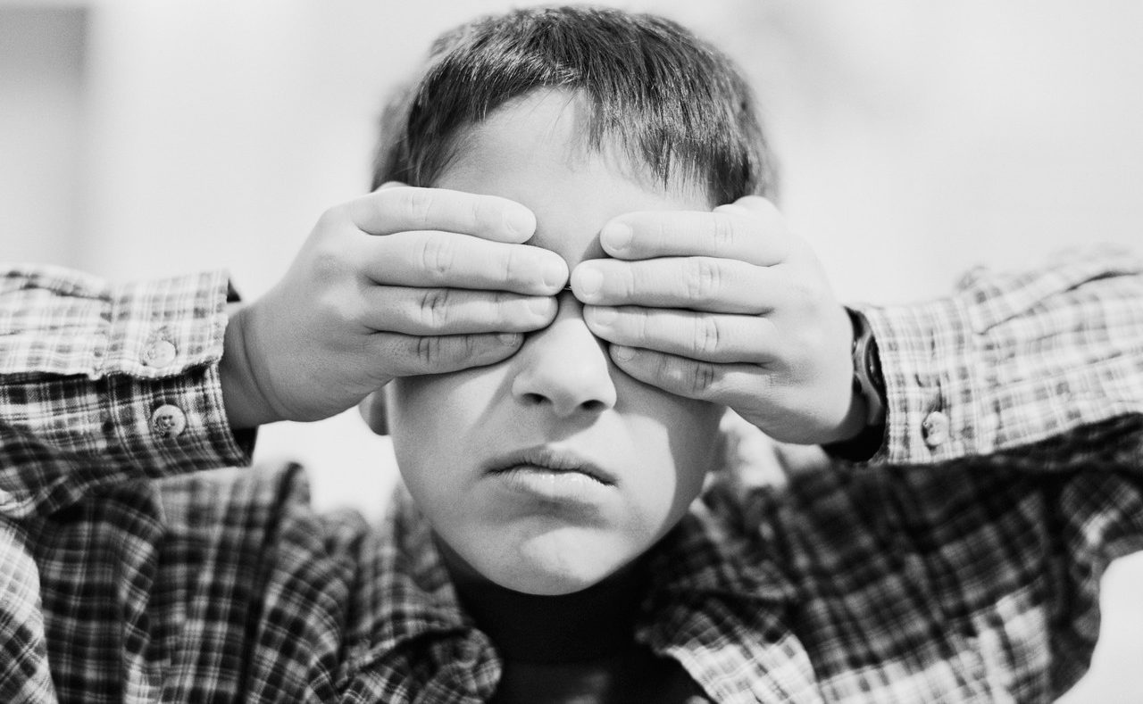 Boy holding hands over eyes --- Image by © Stewart Cohen/Blend Images/Corbis