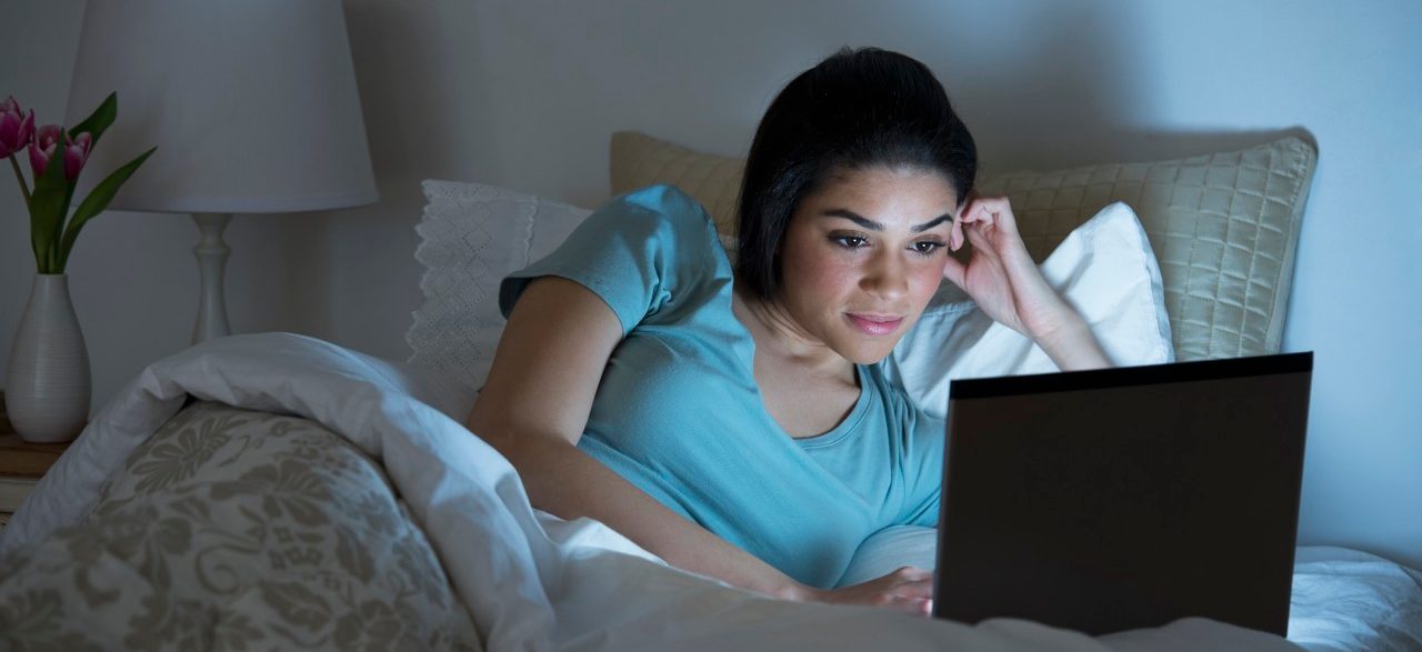 USA, New Jersey, Jersey City, Young woman using laptop in bed --- Image by © Tetra Images/Corbis