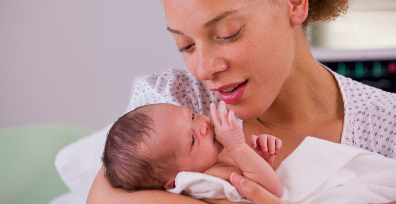 01 Jun 2012, Richmond, Virginia, USA --- Mixed race mother holding newborn baby --- Image by © Ariel Skelley/Blend Images/Corbis