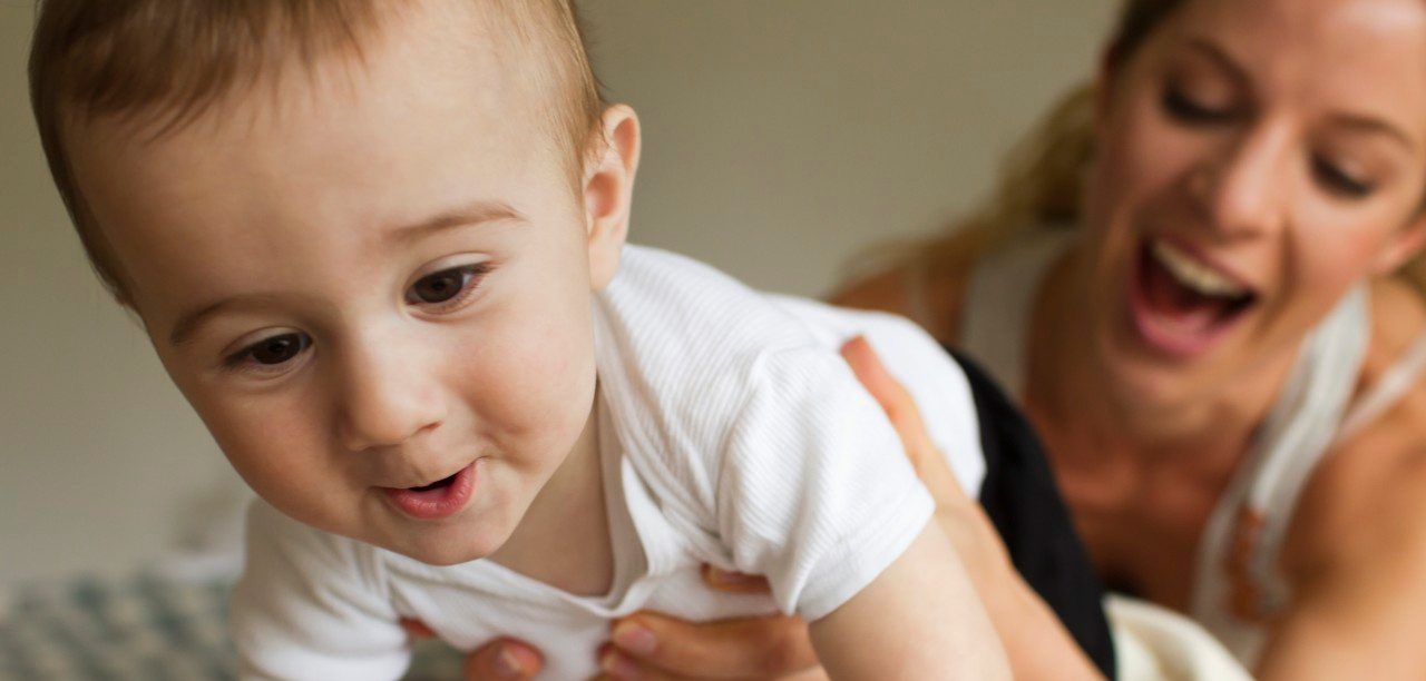 14 Apr 2014 --- Mother guiding baby boy crawling on bed --- Image by © Christine Schneider/Corbis