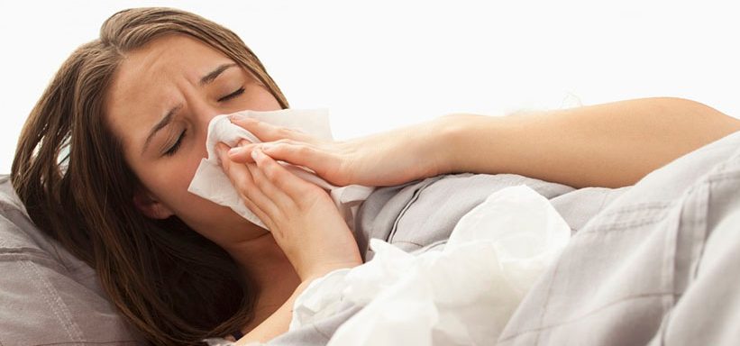 42-29062097 Young woman lying in bed blowing nose --- Image by © Mike Kemp/Tetra Images/Corbis