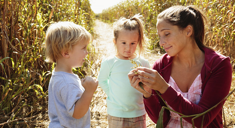 26 Oct 2014 --- Mother with two children in field with crops --- Image by © Corbis