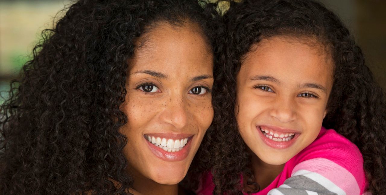13 May 2014, Richmond, Virginia, USA --- Mother and daughter smiling together --- Image by © Ariel Skelley/Blend Images/Corbis