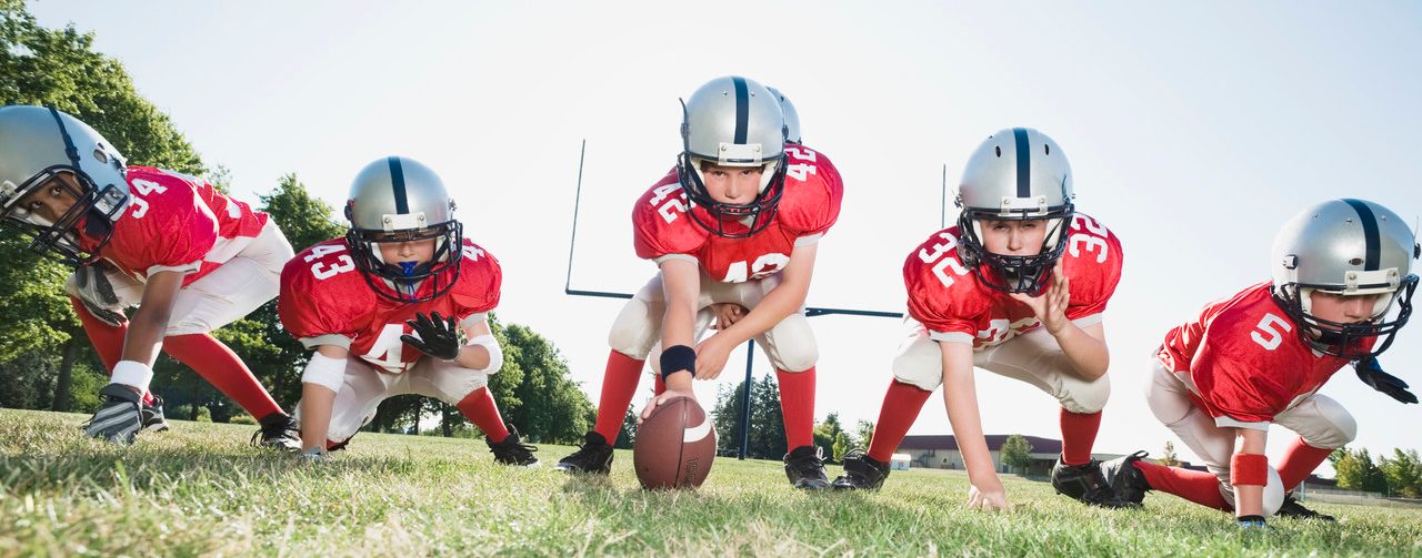 Football players at line of scrimmage ready to snap football --- Image by © Erik Isakson/Tetra Images/Corbis