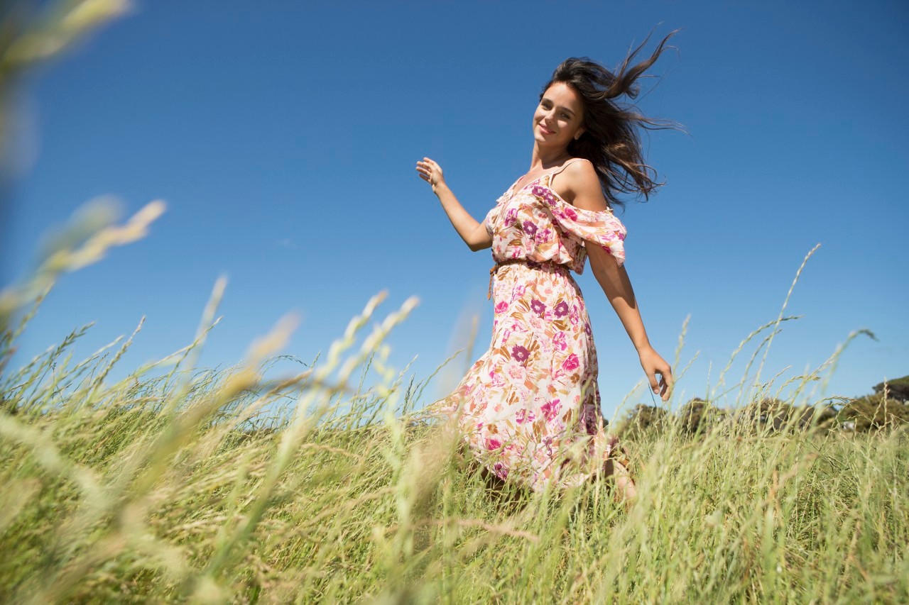 Young woman walking in field with arms raised --- Image by © Tomas Rodriguez/Corbis