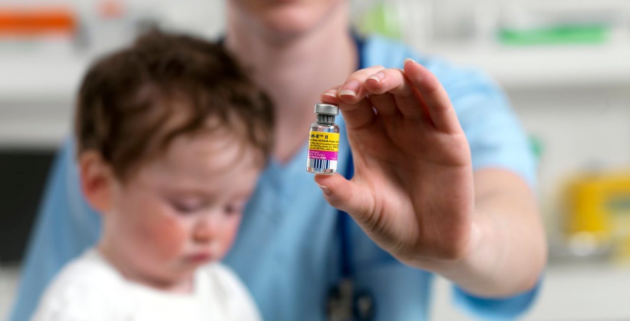 24 Aug 2010 --- MMR vaccine. Paediatrician with a phial of MMR vaccine and a 15 month old boy. --- Image by © TEK IMAGE/Science Photo Library/Corbis