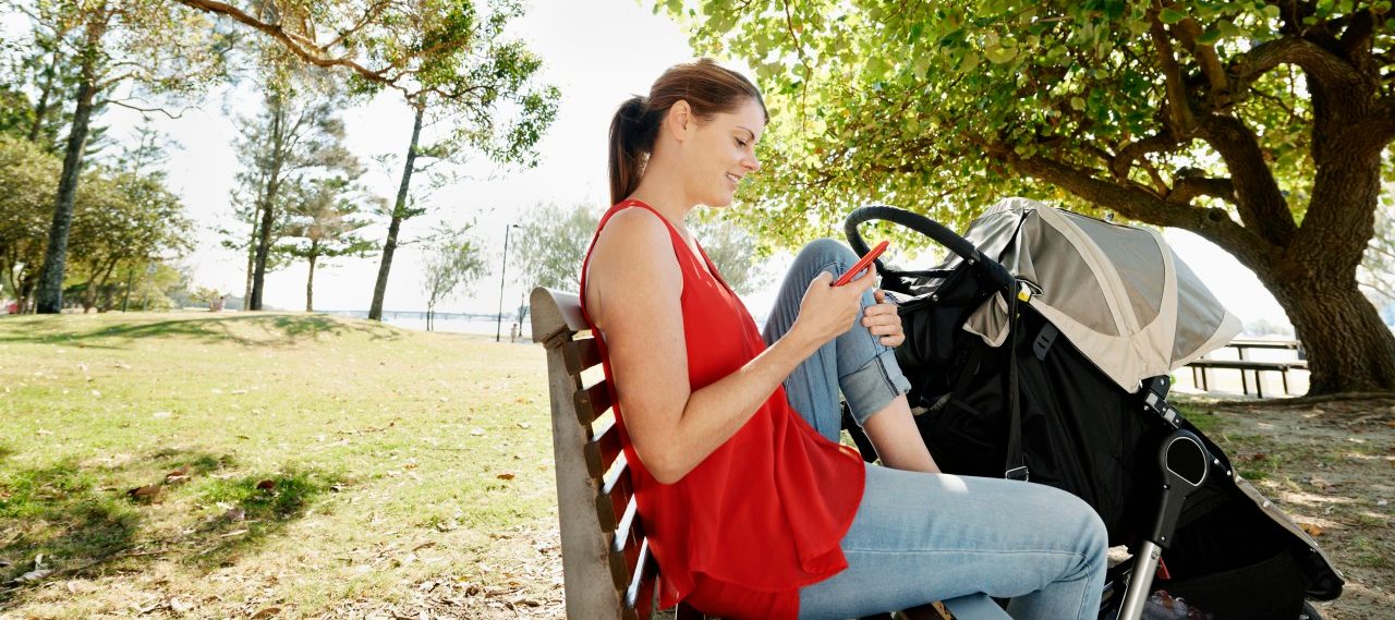 Young mother resting in the shade of the trees on a park bench, texting.Location Gold Coast, Queensland, Australia. --- Image by © Michael Pole/Corbis
