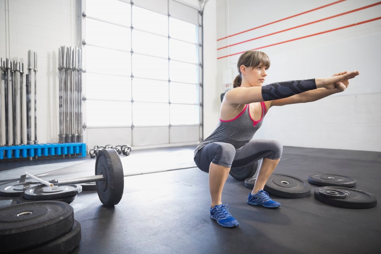 20 Nov 2013, Calgary, Alberta, Canada --- Woman warming up with squats in gym --- Image by © Hero Images/Corbis
