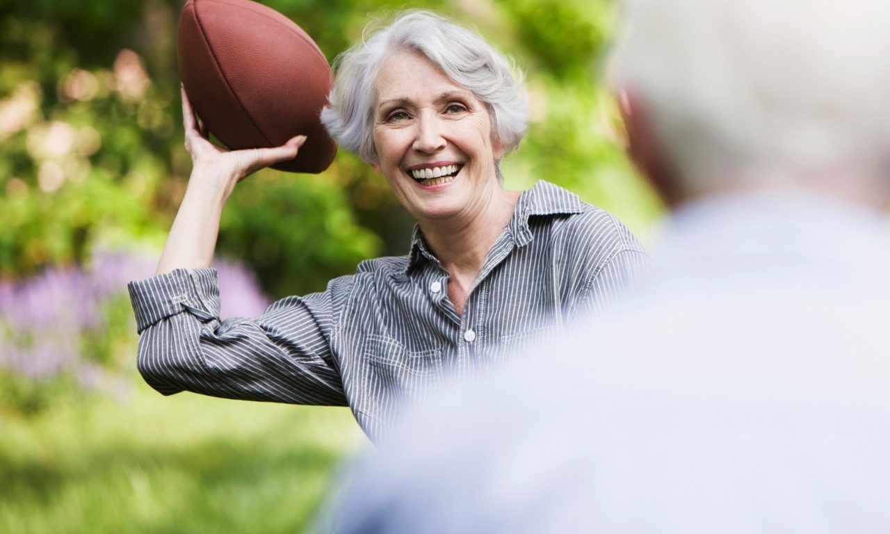 Senior woman throwing football to partner --- Image by © JOSE LUIS PELAEZ, INC./Image Source/Corbis