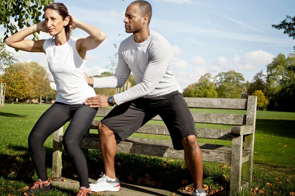 0042-11-30T00:00:00.000Z 24 Oct 2013 --- Man guiding woman doing squats in park --- Image by © Vincent Starr Photography/Corbis