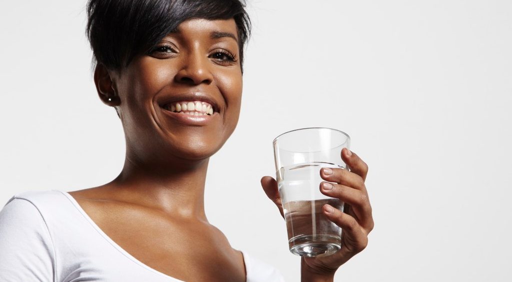 Studio portrait of woman holding glass of water --- Image by © pinkypills/Corbis