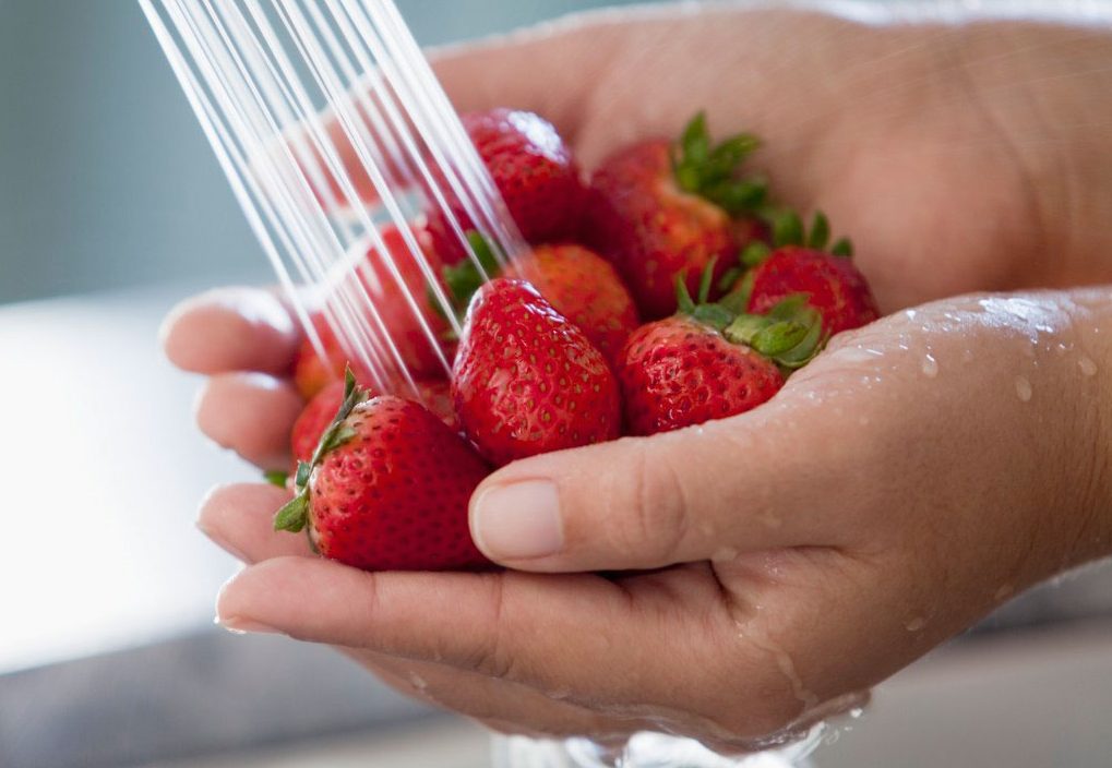 A person ashing strawberries in a sink