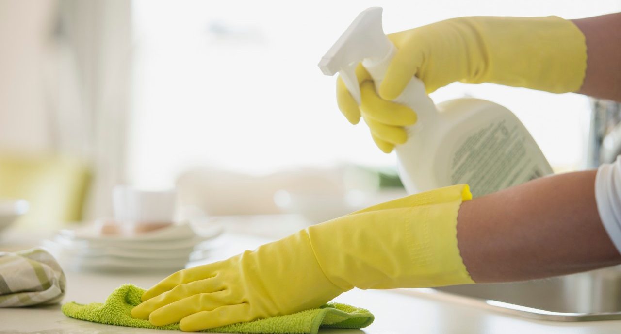 04 Oct 2012 --- Woman in rubber gloves using spray cleaner on counter. --- Image by © Hero Images/Corbis
