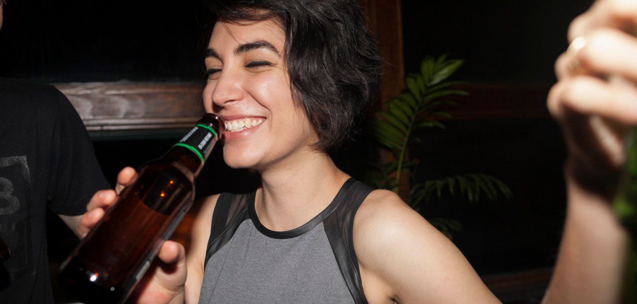 16 Aug 2014 --- Young woman enjoying a beer at a party --- Image by © HEX/Corbis