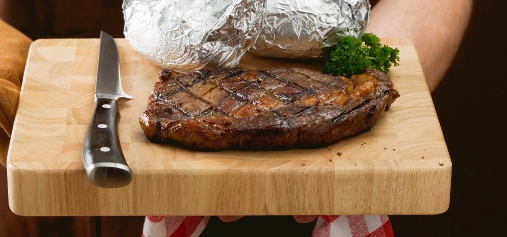 02 May 2007 --- Man holding grilled beef steak on chopping board --- Image by © the food passionates/Corbis